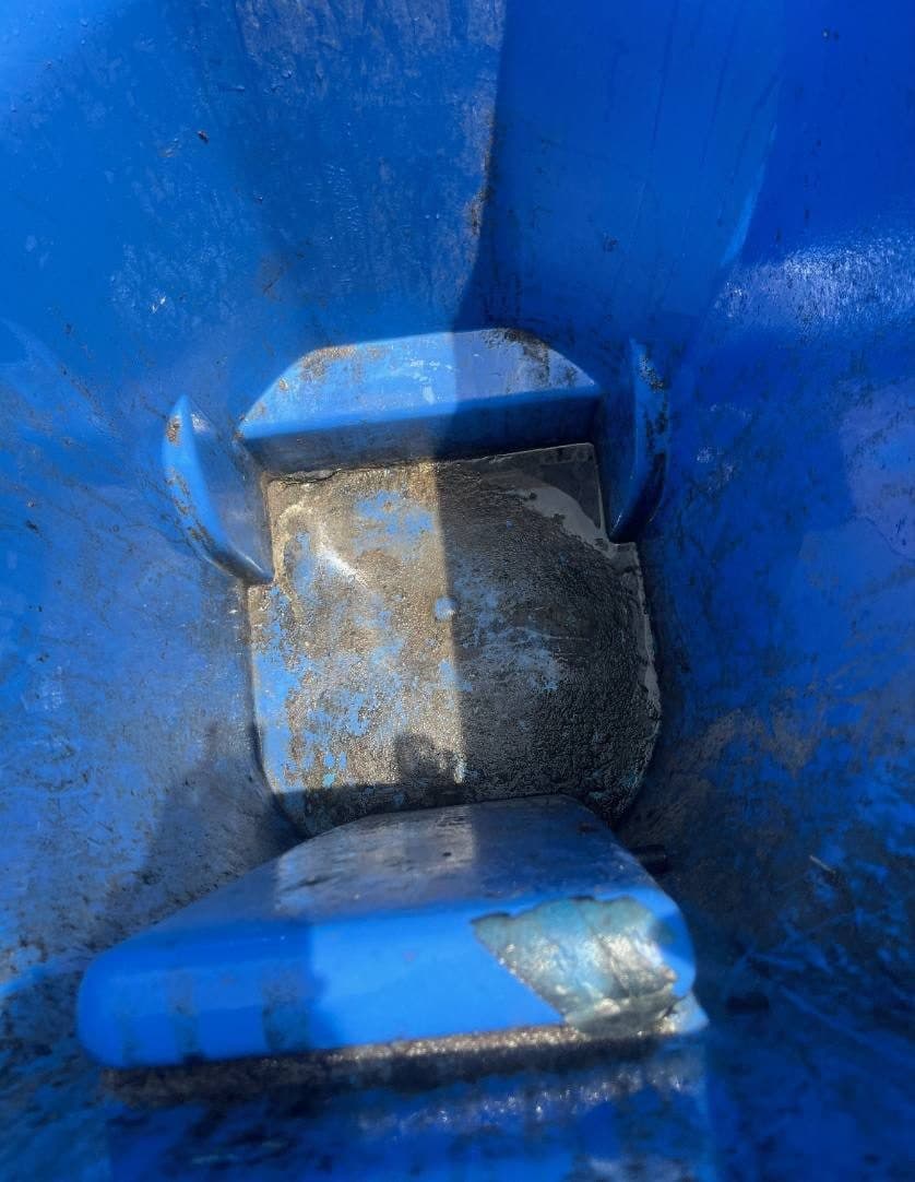 Inside of a trash bin caked with black grime and debris before cleaning